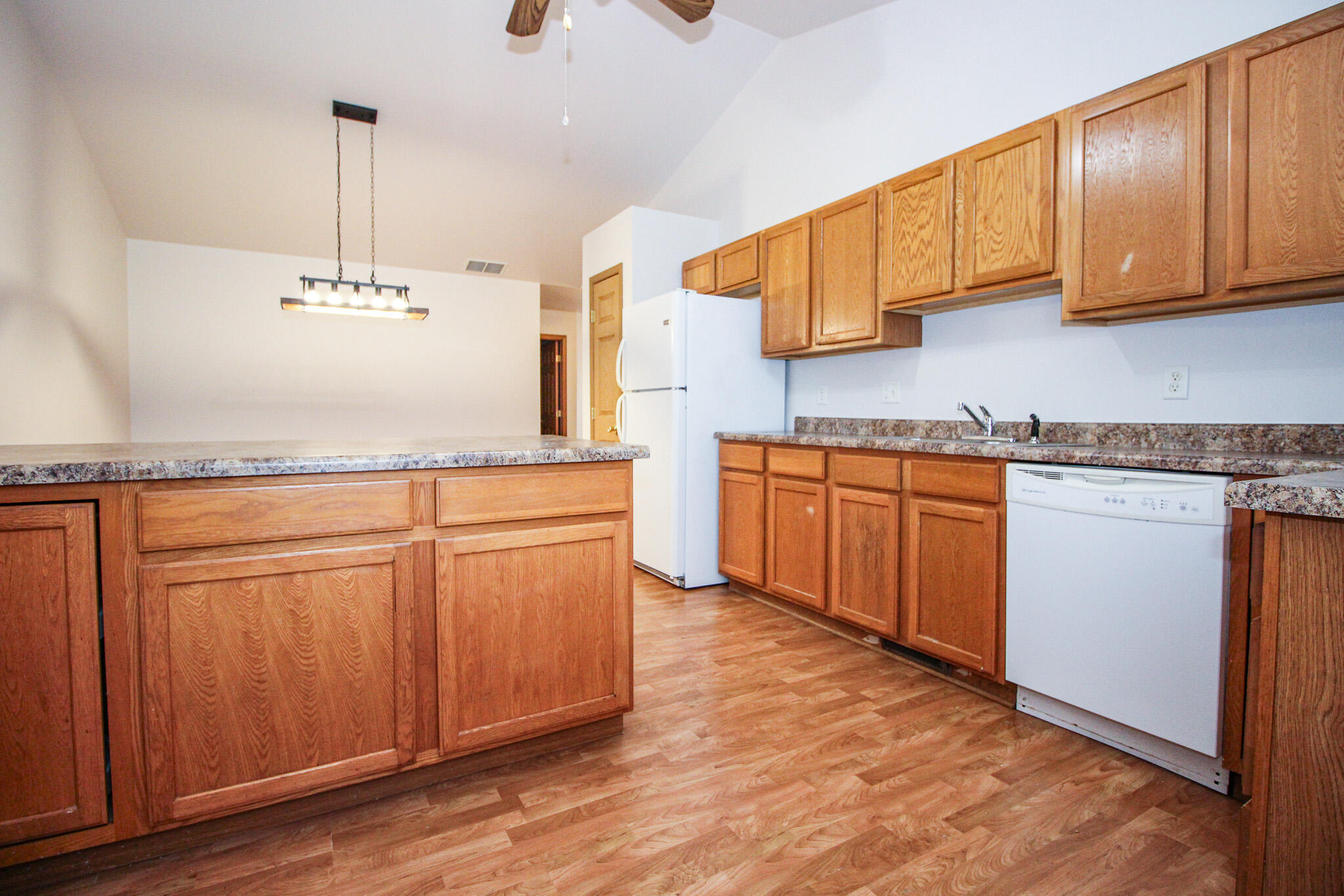 1709 Daisy Street Southeast De Motte, IN 46310 - Photo 9 of 19 a kitchen with kitchen island granite countertop wooden cabinets and white appliances