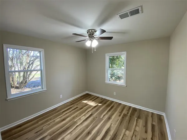 a view of an empty room with window and wooden floor