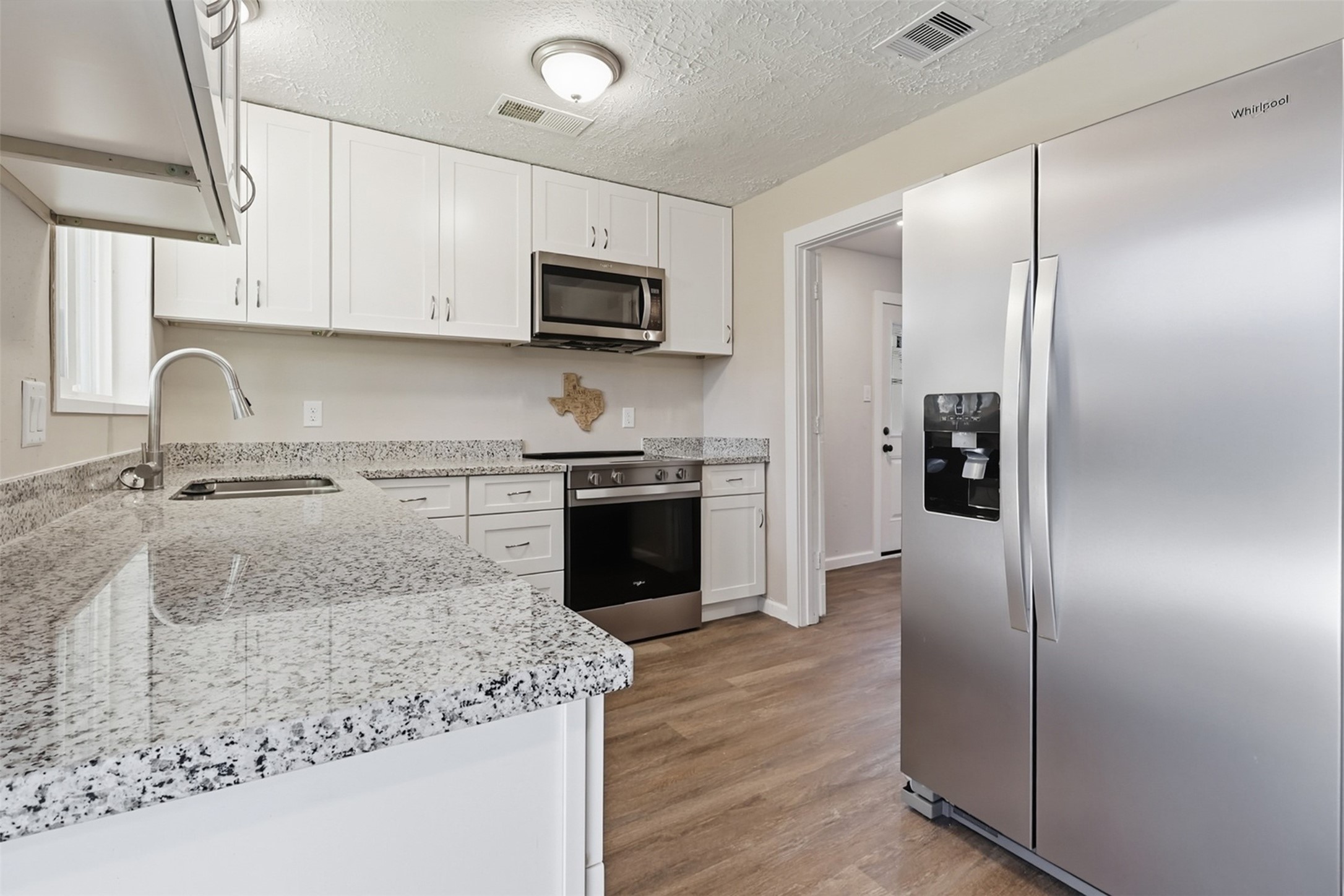 4767 Beechaven Street Houston, TX 77053 - Photo 6 of 26 a kitchen with stainless steel appliances granite countertop a refrigerator a stove and a sink with wooden floor