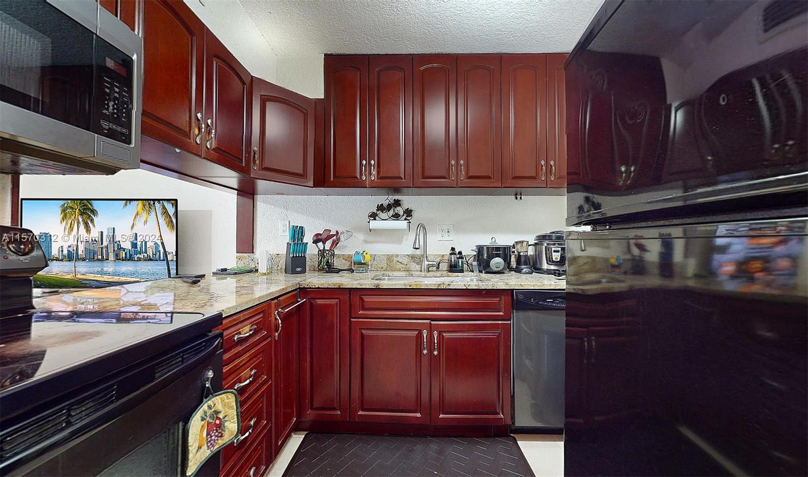 9483 Southwest 76th Street, Unit N3 Miami, FL 33173 - Photo 2 of 27 a kitchen with stainless steel appliances granite countertop wooden cabinets a sink and dishwasher