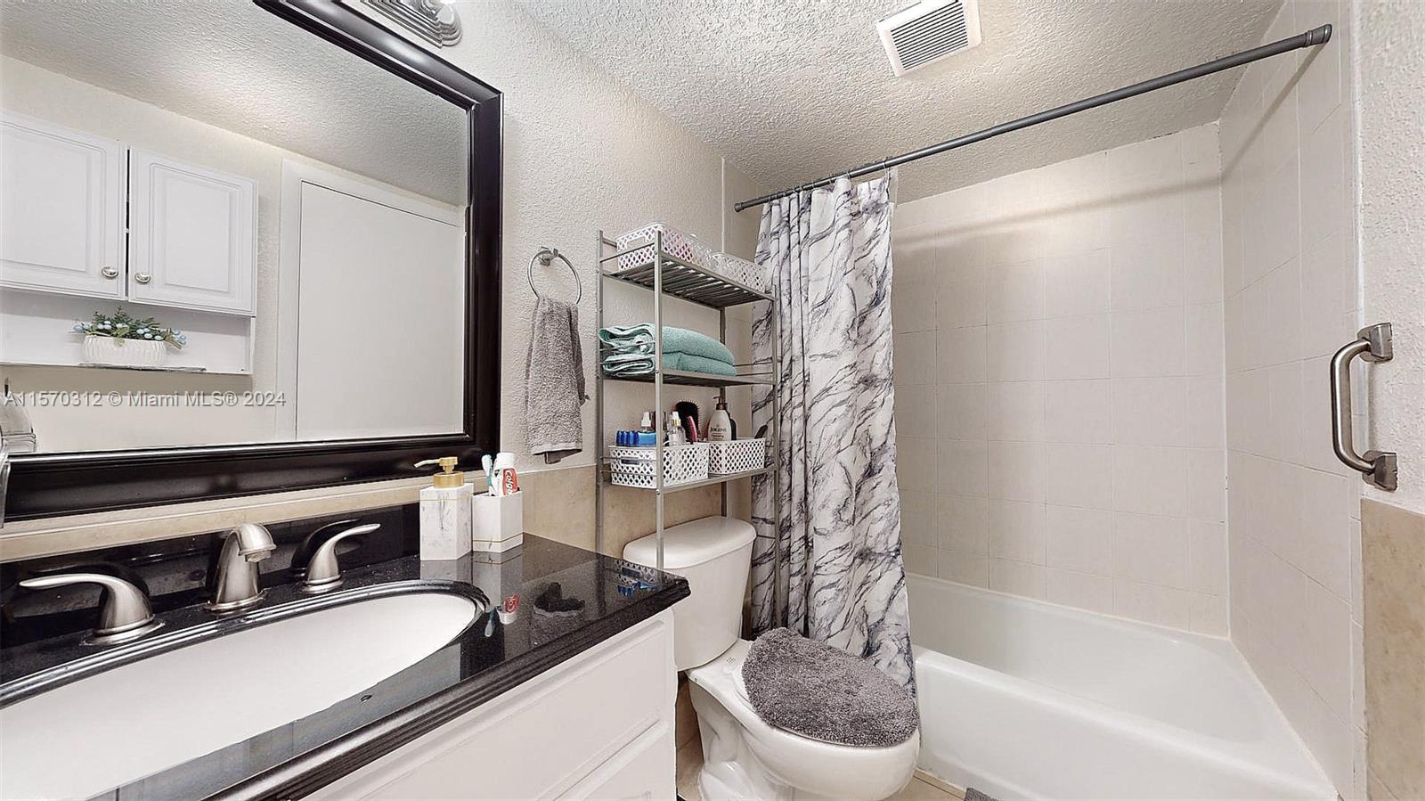 9483 Southwest 76th Street, Unit N3 Miami, FL 33173 - Photo 5 of 27 a bathroom with a granite countertop sink a toilet and bathtub