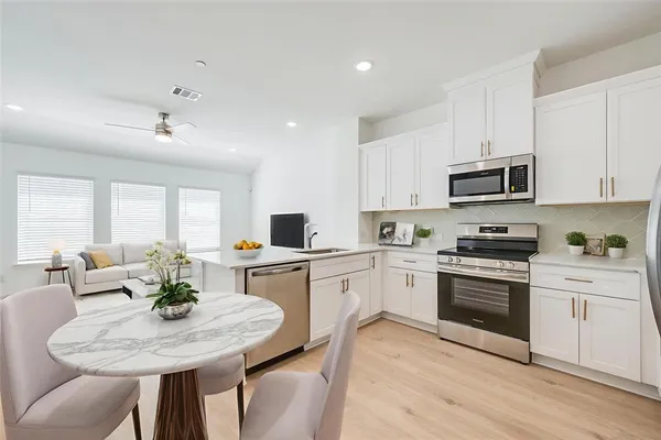 a kitchen with stainless steel appliances granite countertop a stove a sink a microwave a dining table and chairs