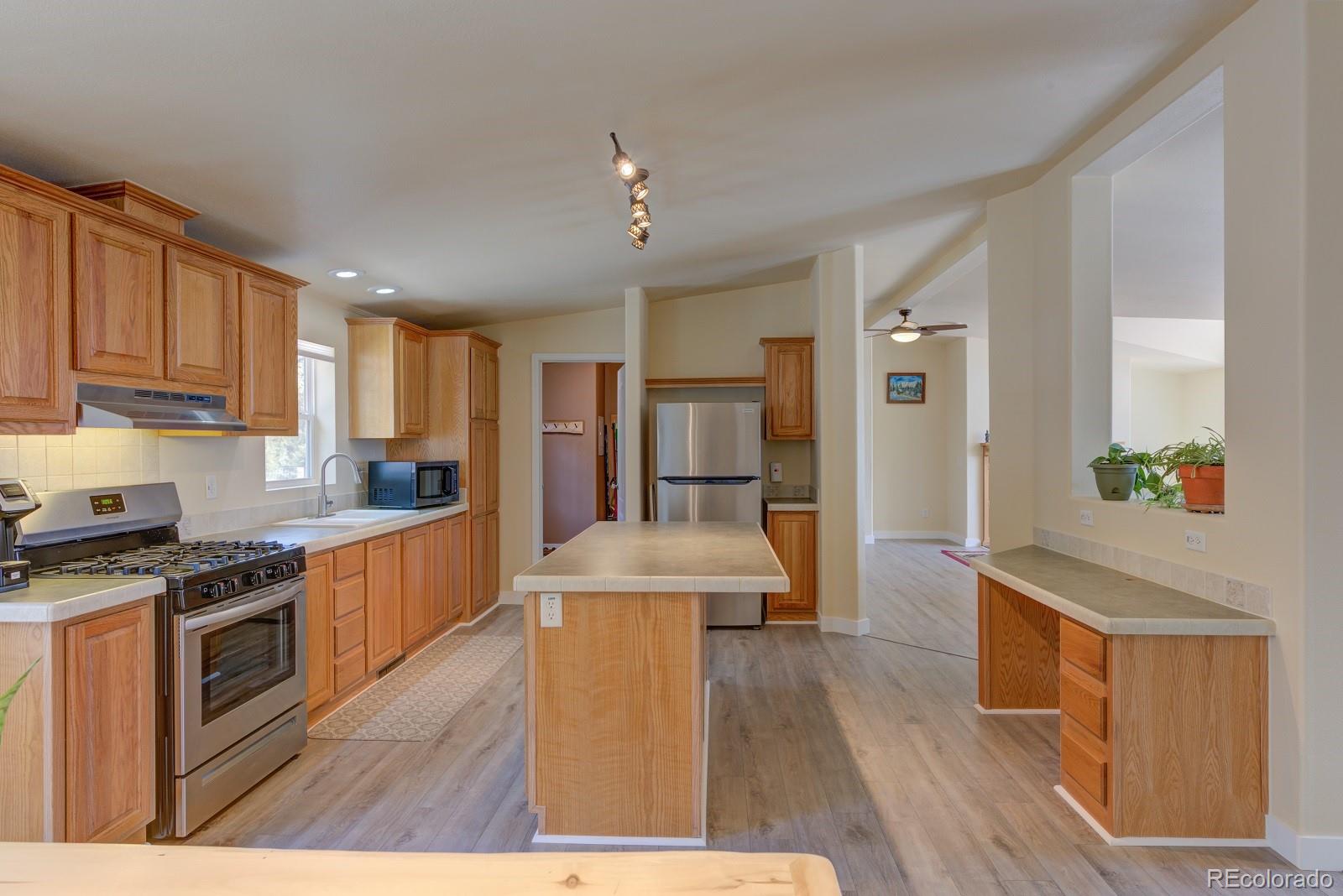 1373 Singletree Road Hartsel, CO 80449 - Photo 17 of 40 a open kitchen with stainless steel appliances granite countertop a stove top oven a refrigerator a sink dishwasher with wooden cabinets and wooden floor