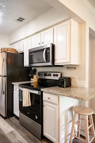 a kitchen with stainless steel appliances granite countertop a stove a microwave and a refrigerator