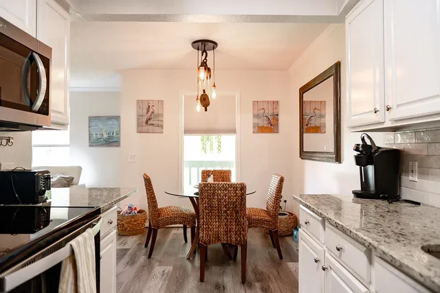 a kitchen with stainless steel appliances granite countertop a table chairs in it and wooden floors
