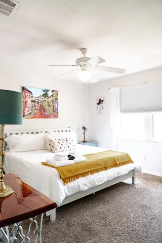 a white bed sitting in a bedroom next to a window with a chandelier