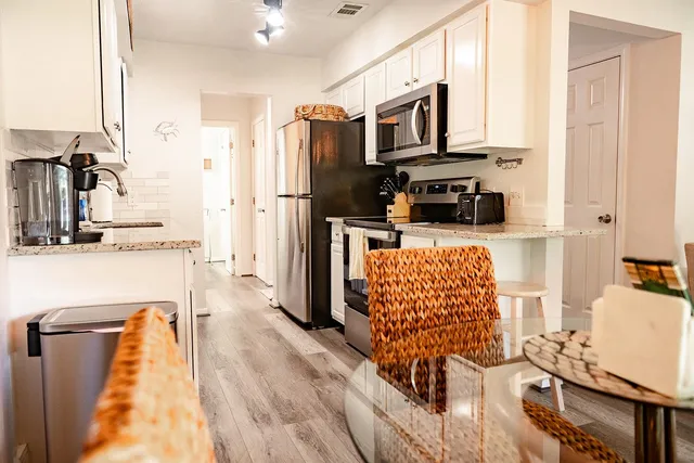 a kitchen with stainless steel appliances granite countertop a refrigerator a stove top oven a sink dishwasher and dining table with wooden floor