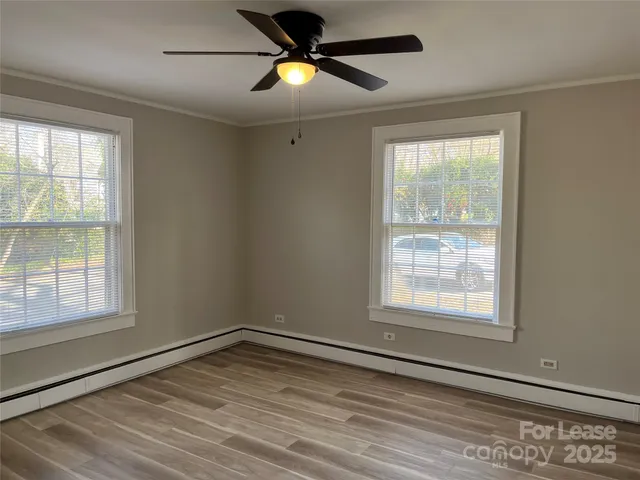 a view of empty room with wooden floor and fan