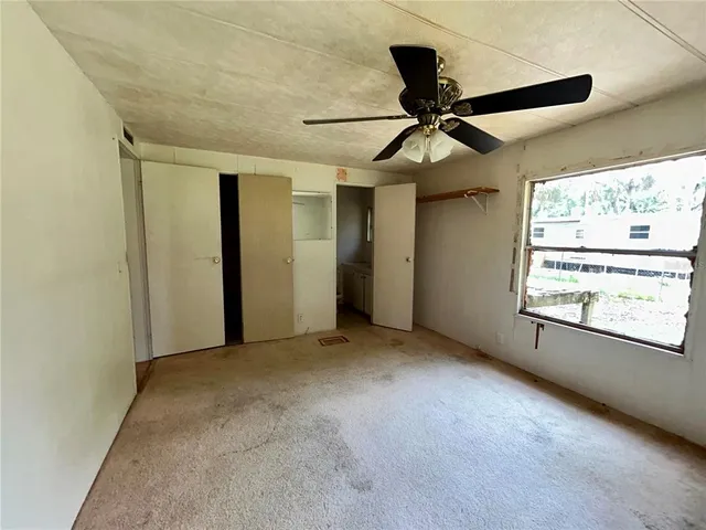 an empty room with windows and fan