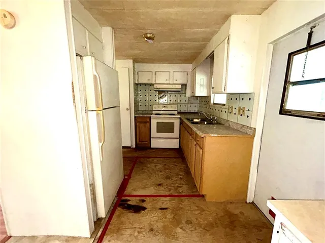 a kitchen with stainless steel appliances granite countertop a refrigerator a stove a sink and a window