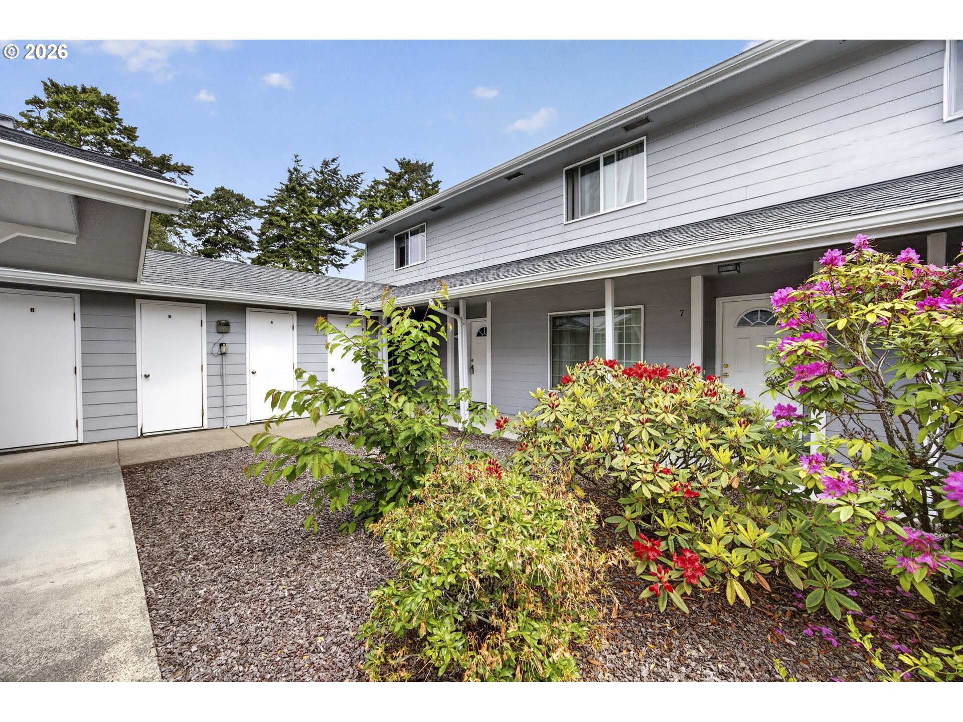 1150 Hemlock Street, Unit B8 Florence, OR 97439 - Photo 20 of 24 a front view of a house with lots of flower plants