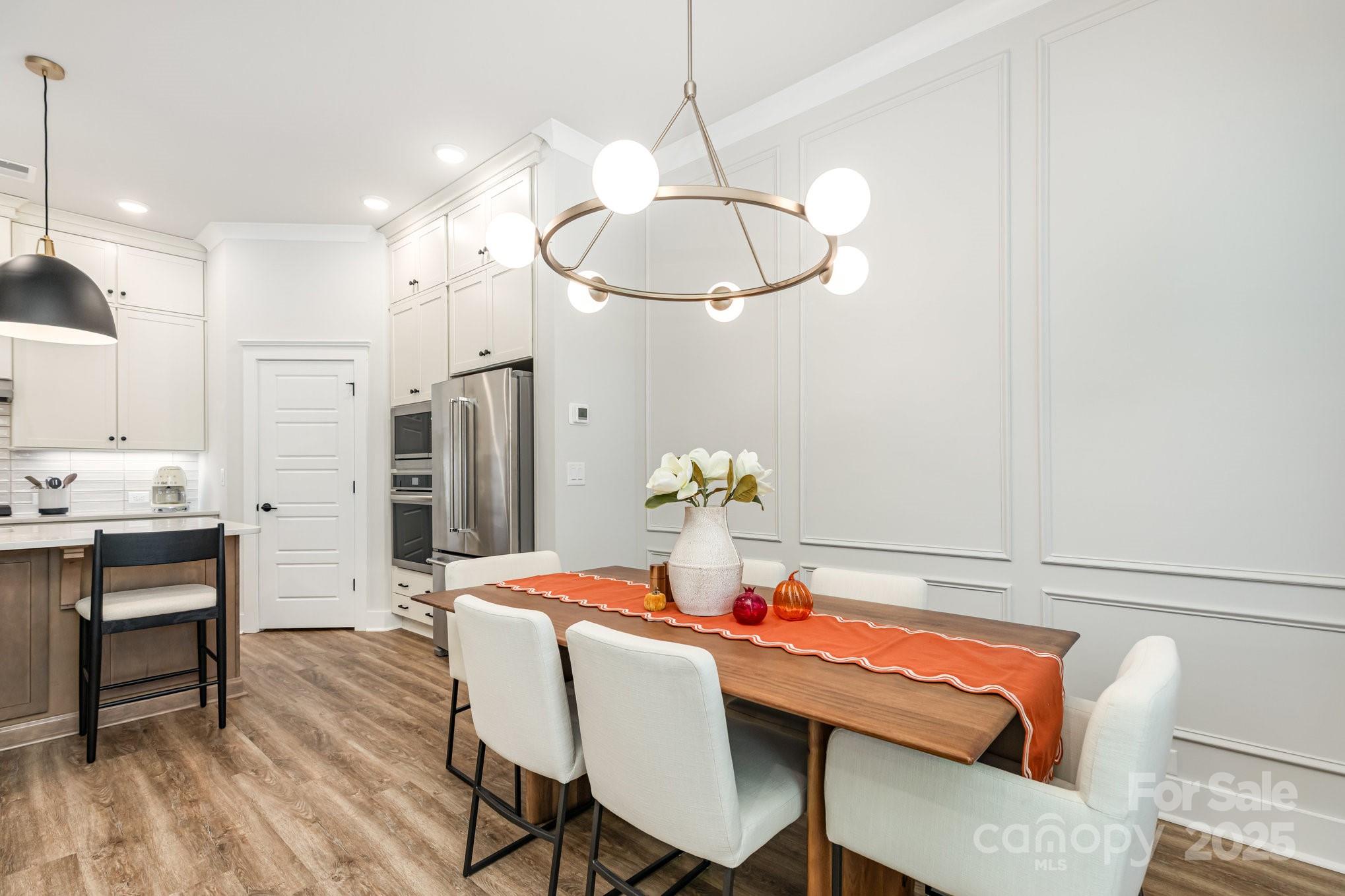 8014 Houser Street Cornelius, NC 28031 - Photo 6 of 24 a dining room with furniture a chandelier and wooden floor