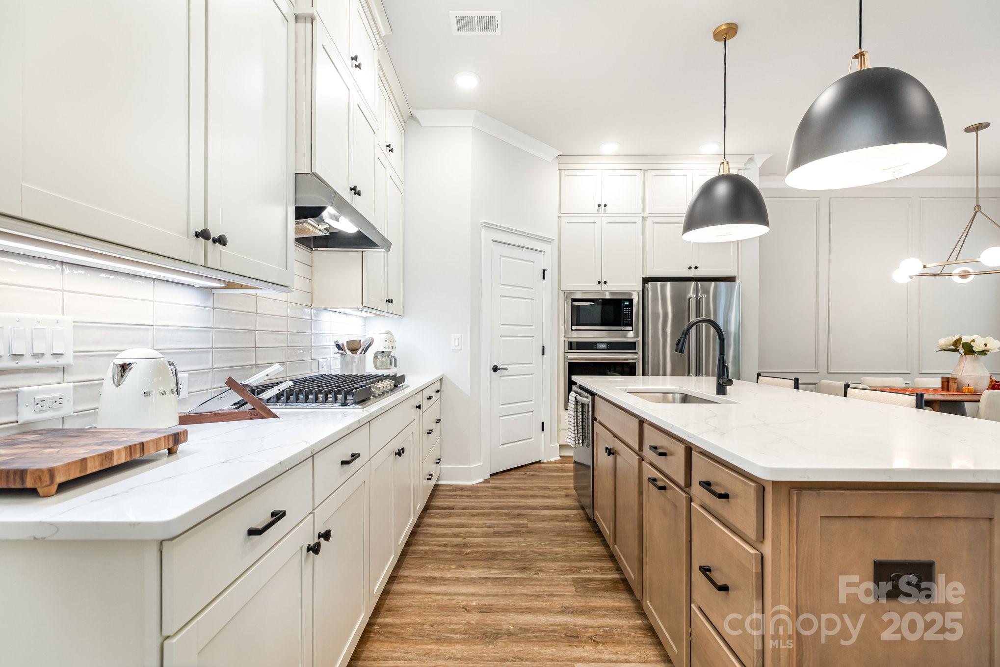 8014 Houser Street Cornelius, NC 28031 - Photo 10 of 24 a large kitchen with kitchen island a sink a counter space a stove and a wooden floors