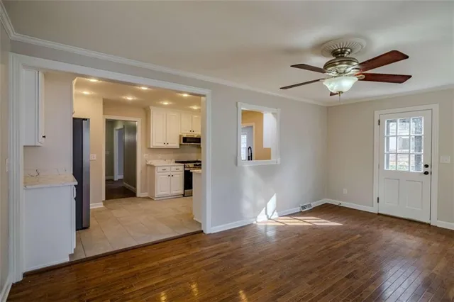 a view of empty room with wooden floor and fan