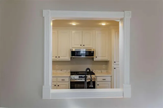 a kitchen with stainless steel appliances a stove and white cabinets