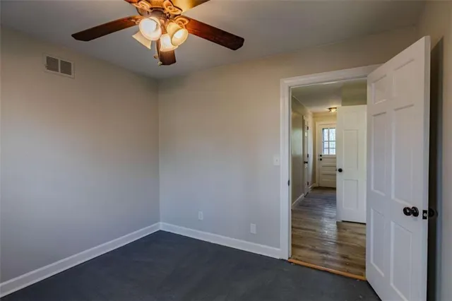 an empty room and chandelier fan in hallway