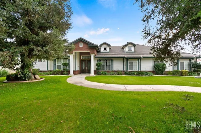 a view of a white house with a big yard and large trees