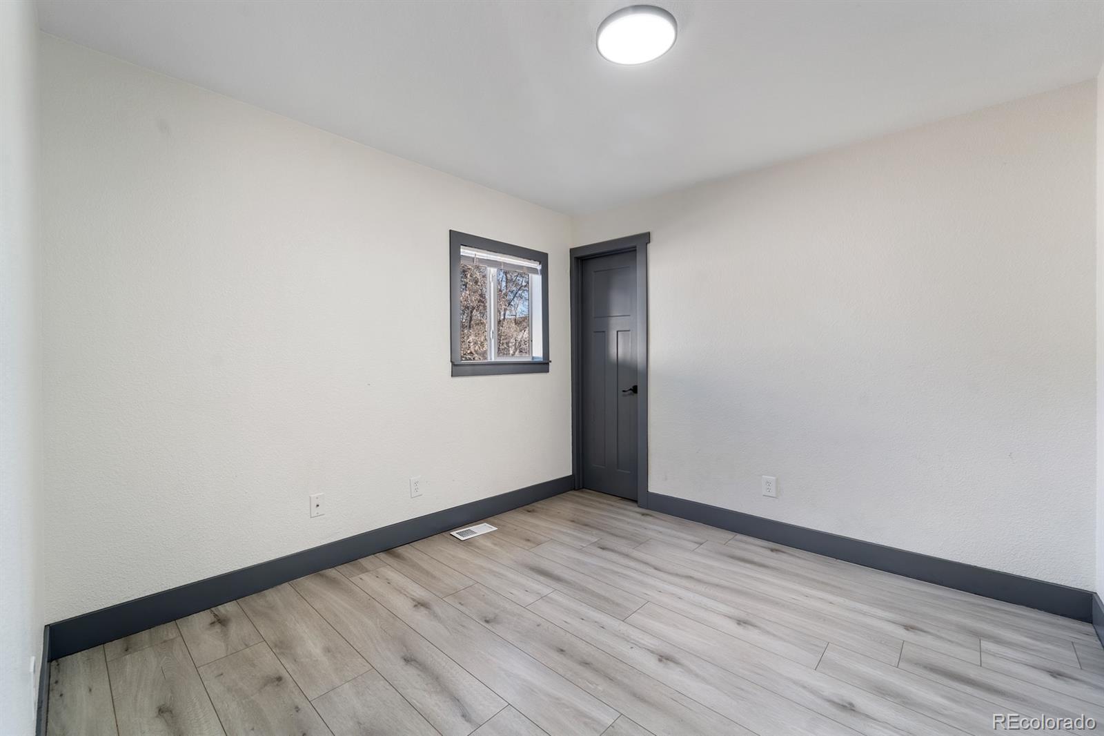 104 Stuart Street Denver, CO 80219 - Photo 11 of 18 a view of an empty room with wooden floor and a window