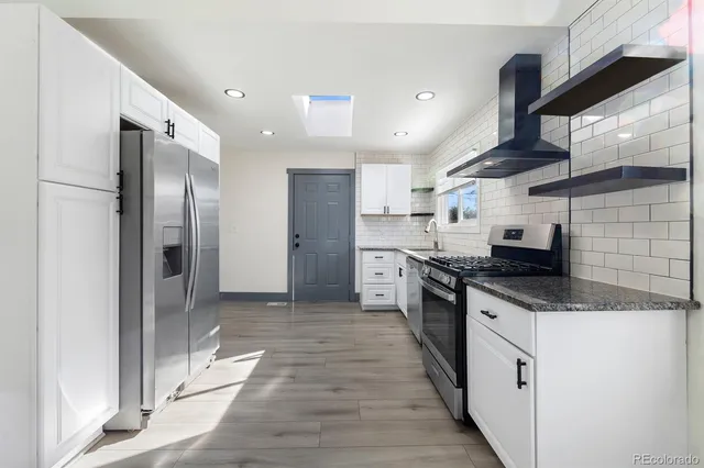 a kitchen with stainless steel appliances granite countertop a sink a stove and a refrigerator