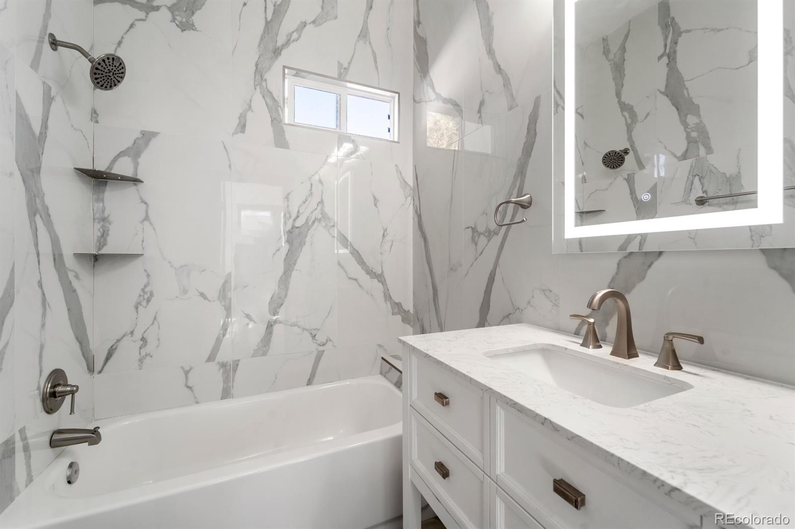 104 Stuart Street Denver, CO 80219 - Photo 7 of 18 a bathroom with a tub sink and mirror
