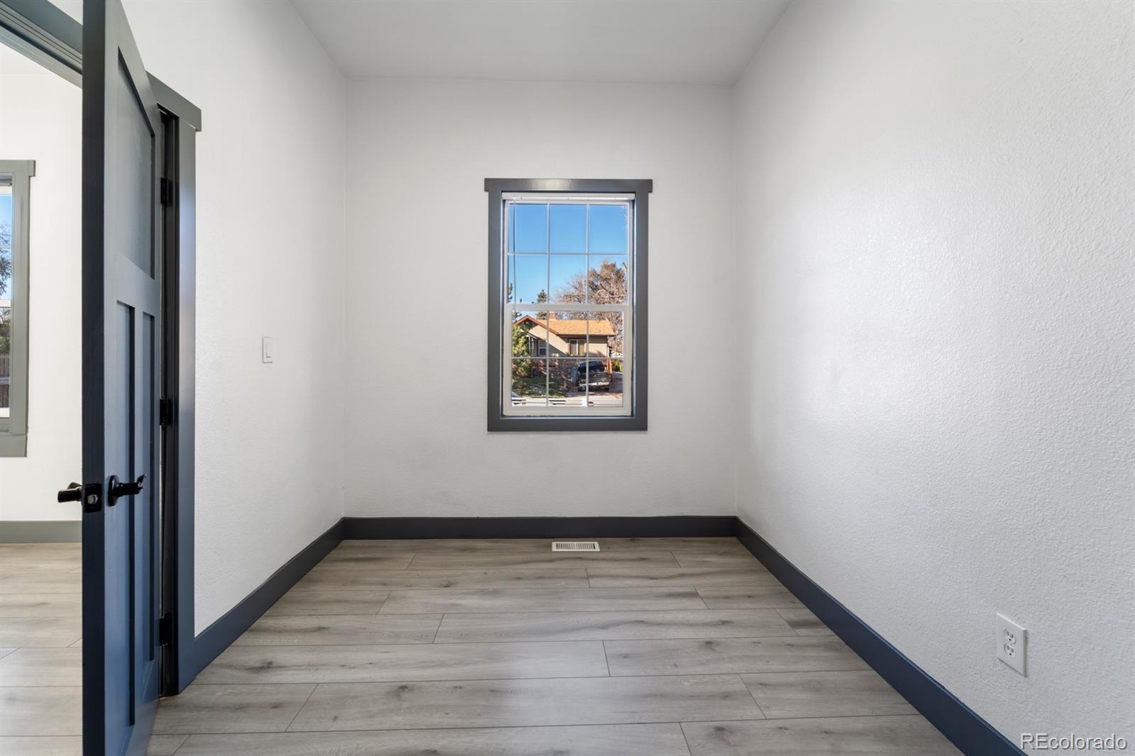 104 Stuart Street Denver, CO 80219 - Photo 9 of 18 a view of an empty room with wooden floor and a window