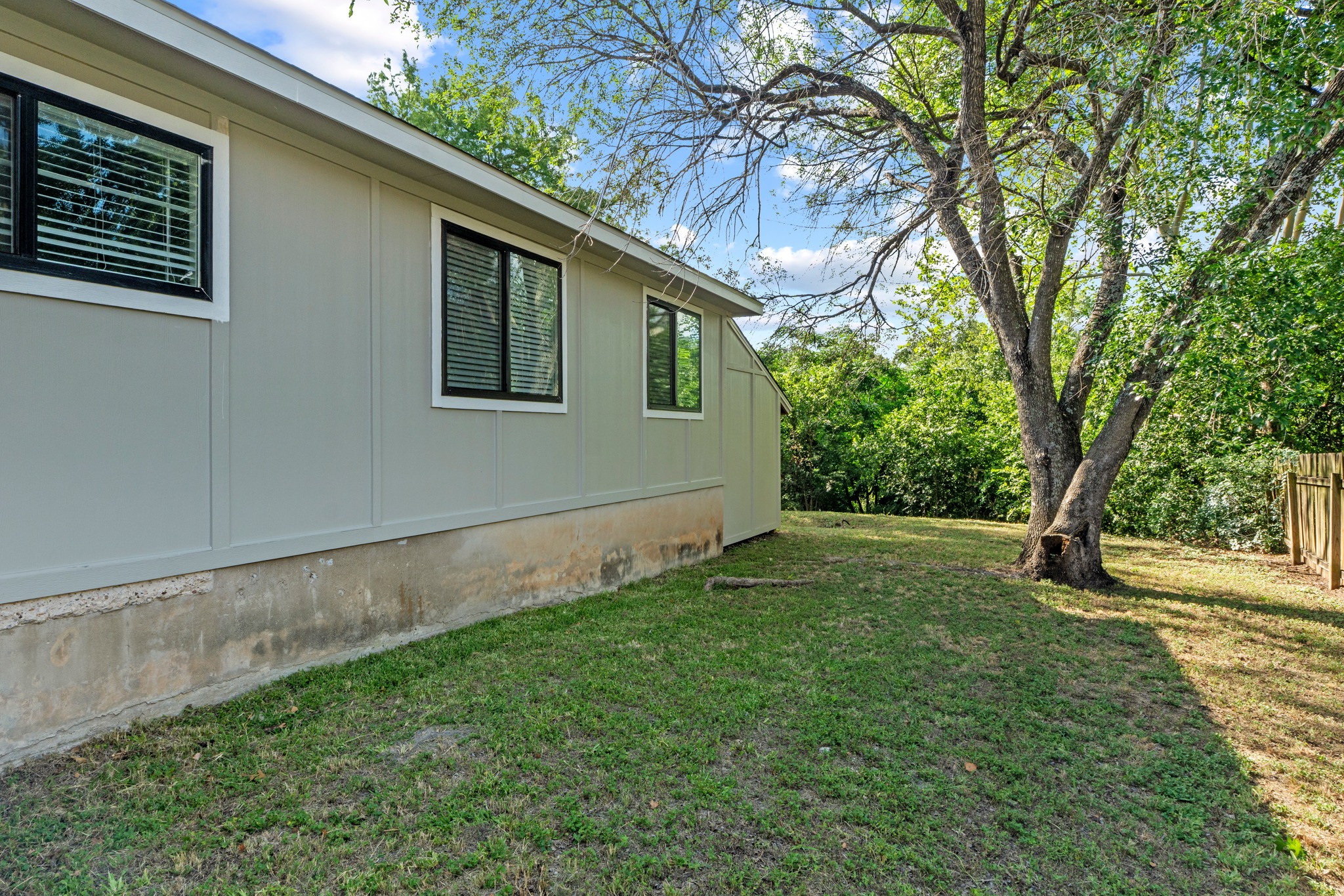 11811 Rotherham Drive Austin, TX 78754 - Photo 37 of 37 A well-maintained side exterior of the structure features ample yard space, framed by mature trees.