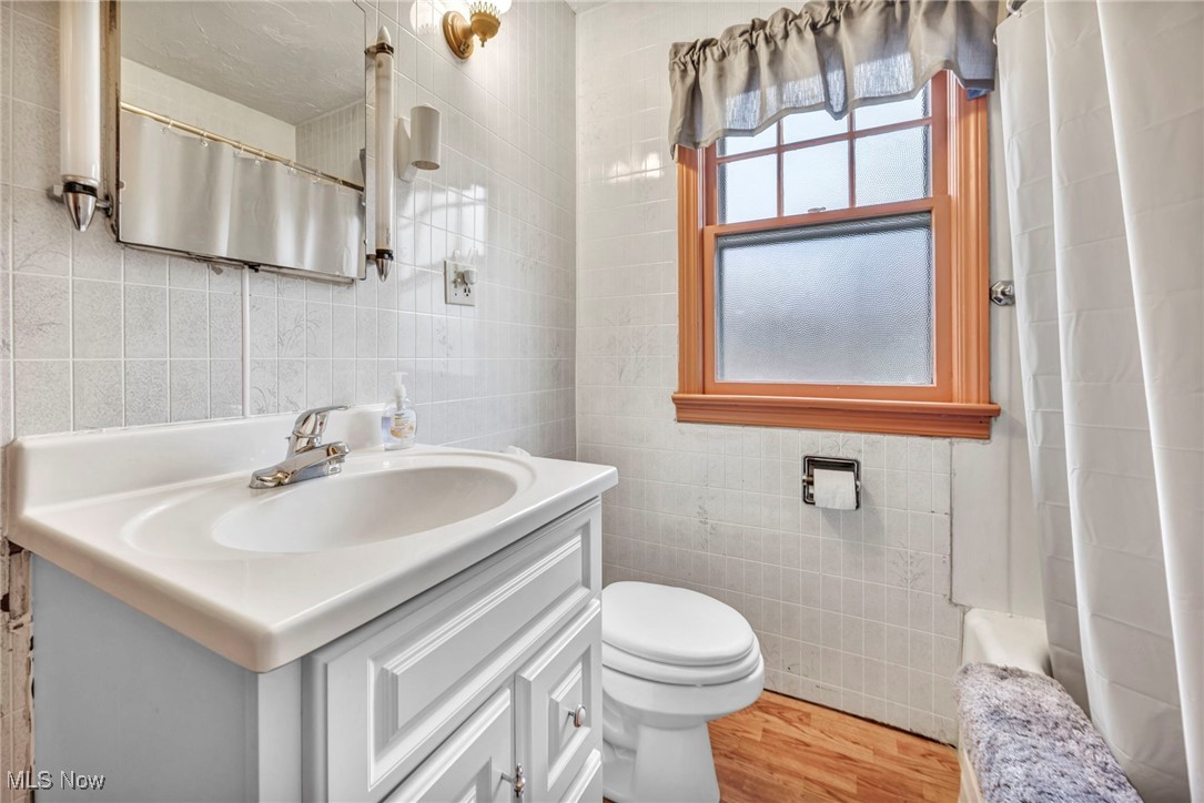 9982 Crow Road Litchfield, OH 44253 - Photo 22 of 41 Bathroom with vanity, hardwood / wood-style flooring, toilet, and tile walls