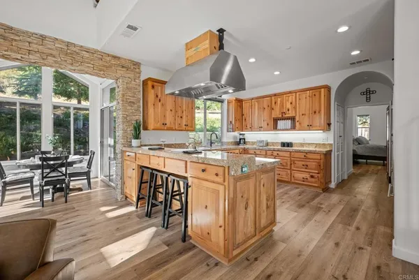 a large kitchen with kitchen island granite countertop wooden floors and wide window