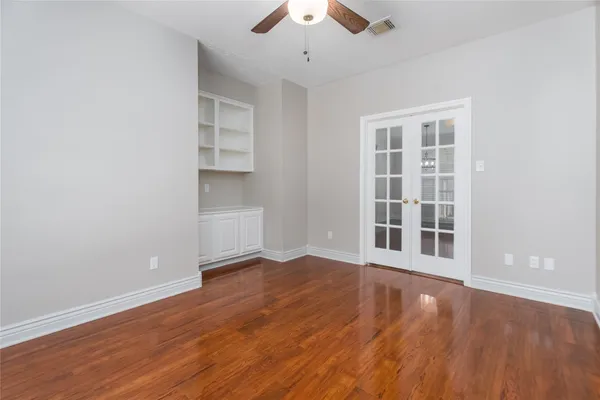an empty room with wooden floor cabinet and windows