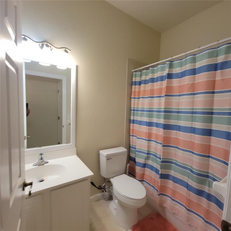 3351 Whitestone Circle, Unit 105 Kissimmee, FL 34741 - Photo 20 of 22 a bathroom with a sink a toilet a mirror and shower curtain