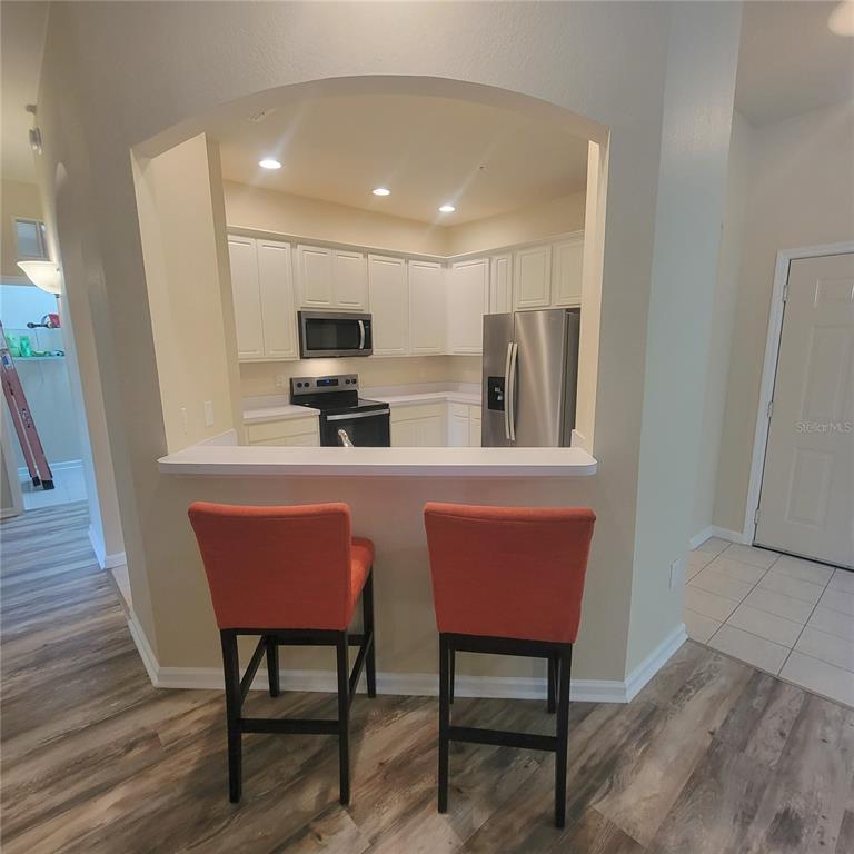 3351 Whitestone Circle, Unit 105 Kissimmee, FL 34741 - Photo 8 of 22 a kitchen with stainless steel appliances granite countertop a dining table chairs microwave and sink