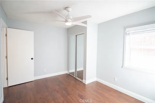 an empty room with wooden floor fan and windows
