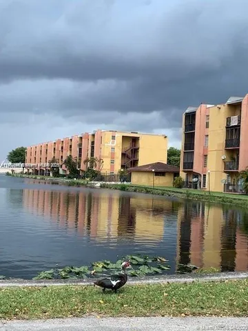 a view of a lake with a big yard and large trees