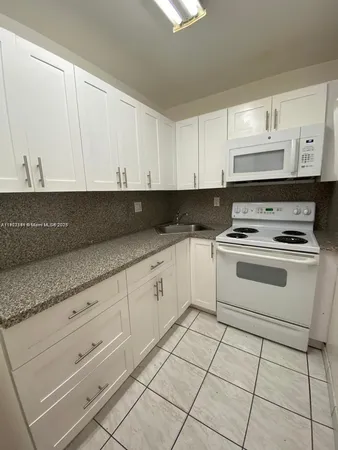 a kitchen with granite countertop white cabinets and white appliances
