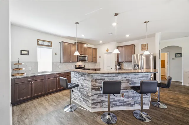 a room with stainless steel appliances kitchen island granite countertop wooden cabinets and a granite counter tops