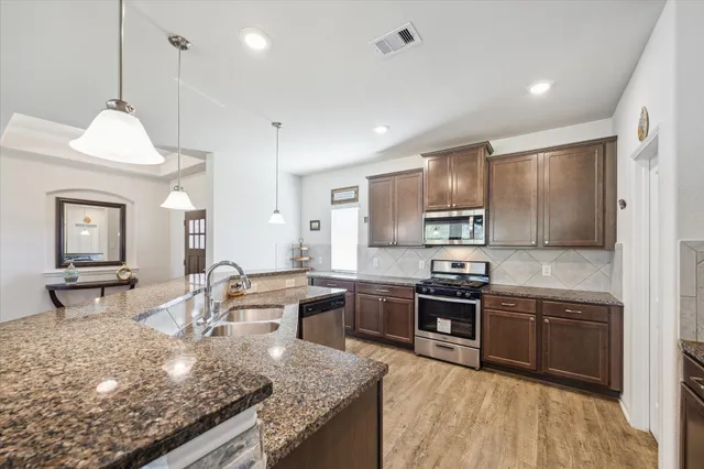 a kitchen with stainless steel appliances granite countertop a sink stove and refrigerator