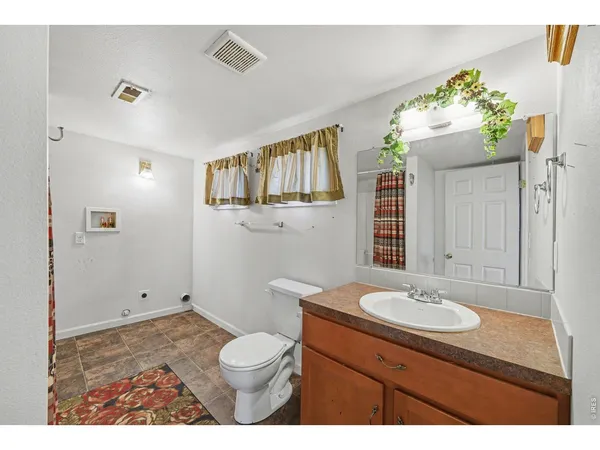 a bathroom with a sink vanity granite toilet and a mirror