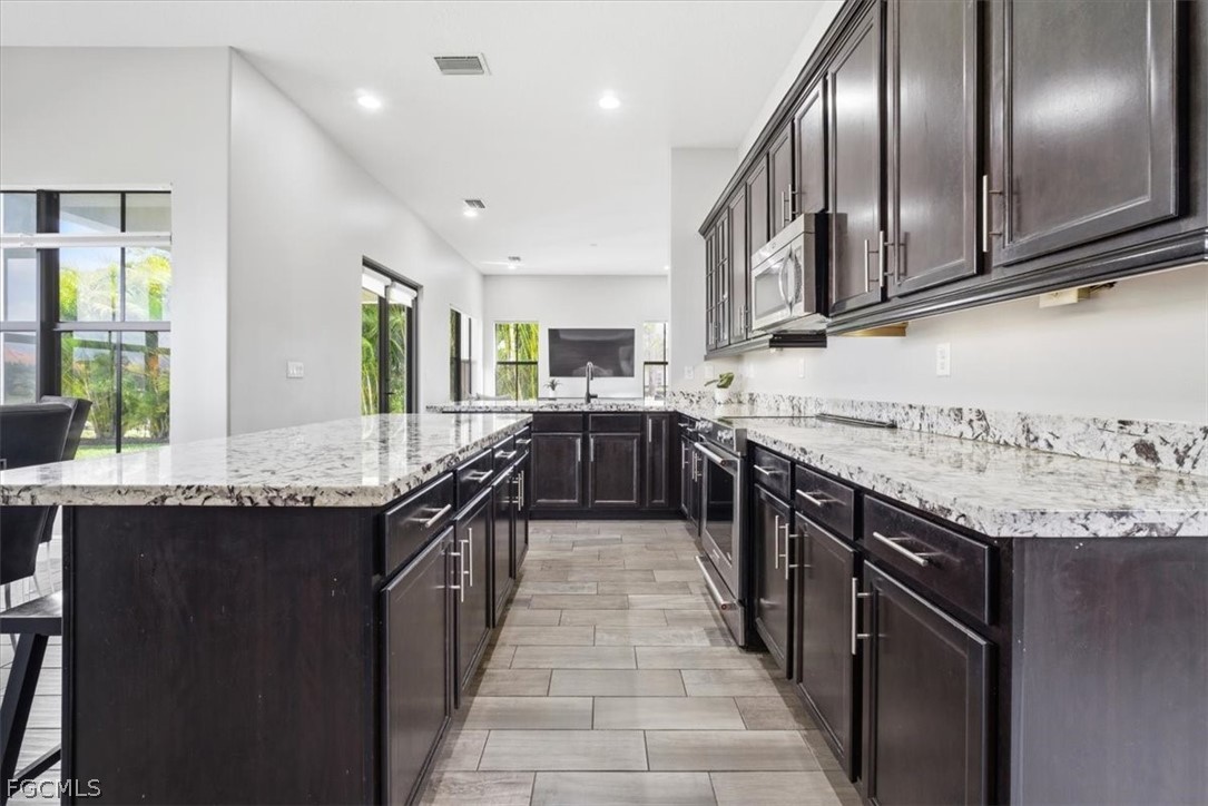 5245 Messina Street Ave Maria, FL 34142 - Photo 11 of 44 a kitchen with stainless steel appliances granite countertop counter space cabinets and a large window