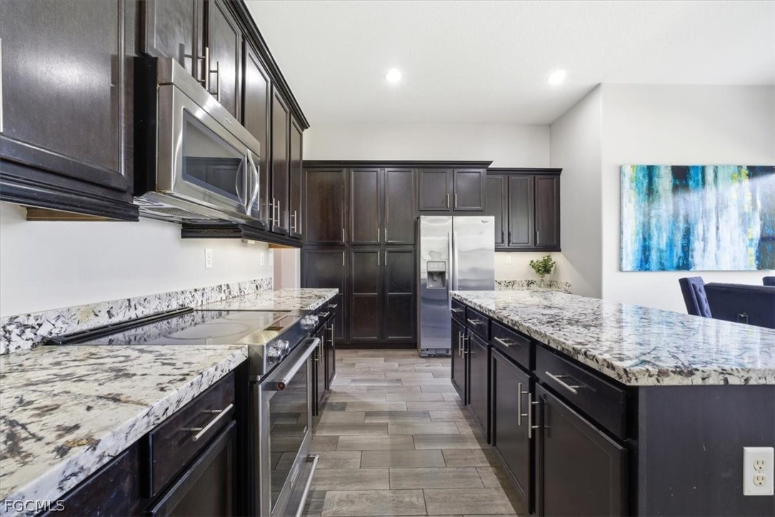 5245 Messina Street Ave Maria, FL 34142 - Photo 12 of 44 a kitchen with granite countertop stainless steel appliances and wooden cabinets