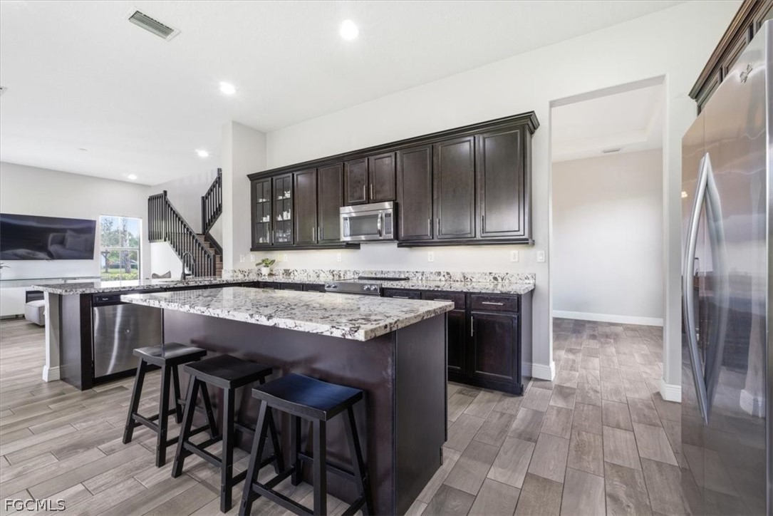 5245 Messina Street Ave Maria, FL 34142 - Photo 10 of 44 a kitchen with stainless steel appliances granite countertop a table chairs sink refrigerator and cabinets