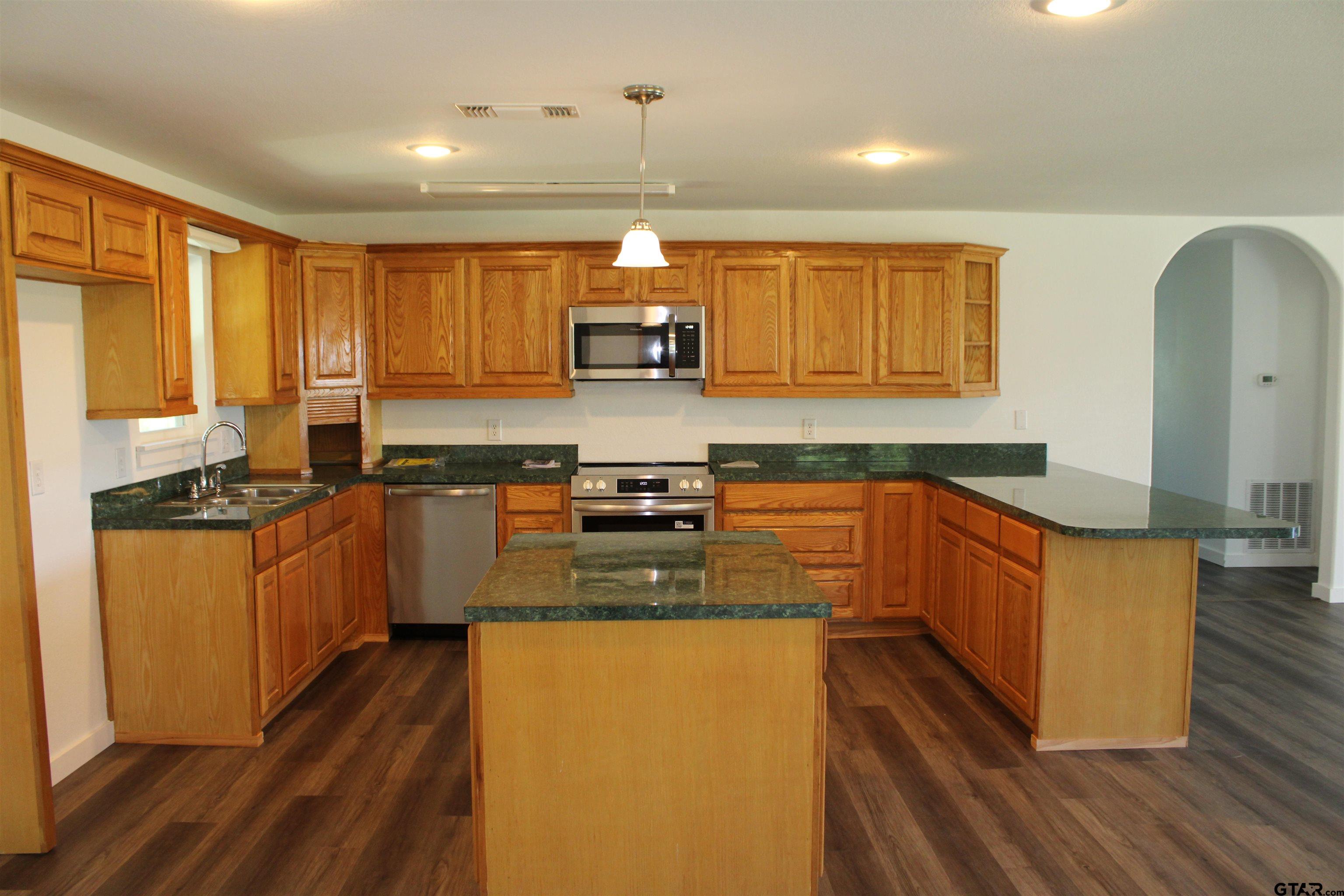 1055 County Road 1314 Rusk, TX 75785 - Photo 22 of 25 a kitchen with stainless steel appliances granite countertop wooden cabinets a refrigerator a sink a stove a microwave and wooden floors