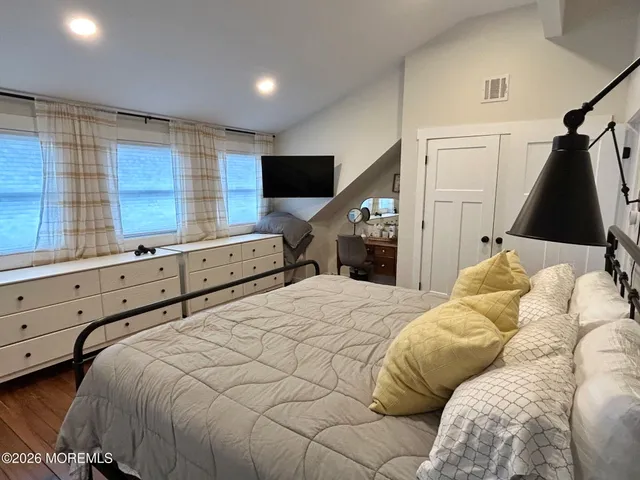 a bedroom with a large bed and a flat tv screen on dresser