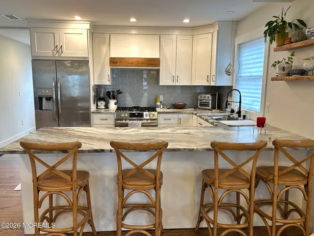 a kitchen with stainless steel appliances granite countertop a table chairs stove refrigerator and sink