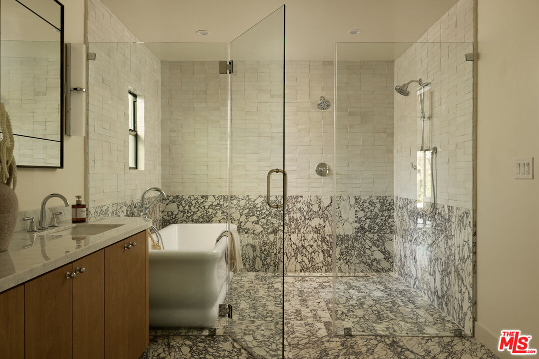 17539 West Magnolia Boulevard Encino, CA 91316 - Photo 19 of 31 a bathroom with a granite countertop sink a mirror and shower