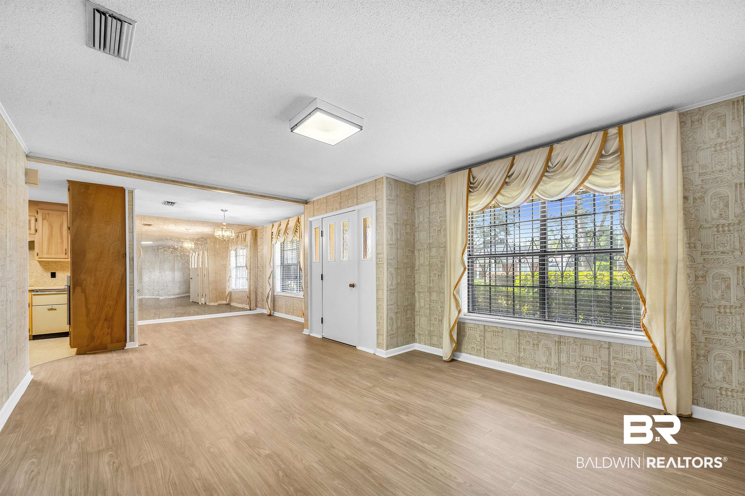610 East Walker Avenue Foley, AL 36535 - Photo 12 of 38 Unfurnished living room with a chandelier, wood finished floors, a textured ceiling, and wallpapered walls