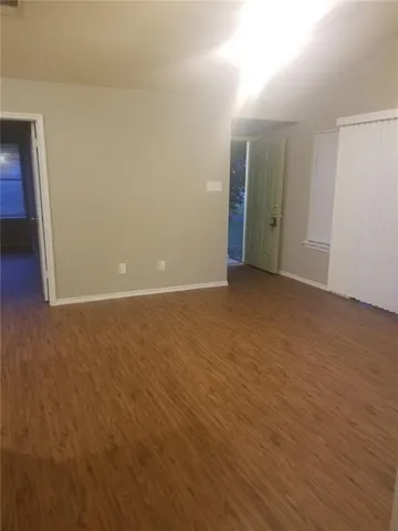 a view of an empty room with wooden floor and closet