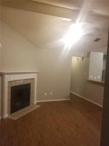 a view of an empty room with wooden floor and a fireplace
