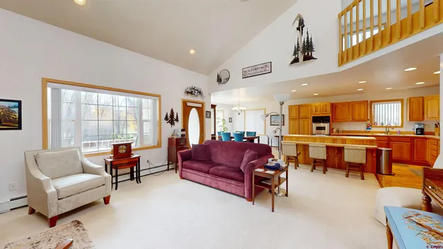 a living room with furniture kitchen view and a large window