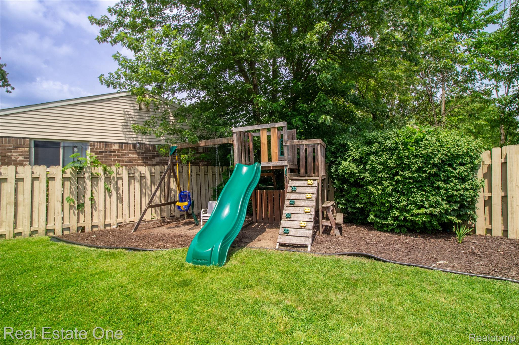 44220 Saltz Road Canton, MI 48187 - Photo 21 of 31 Expansive backyard featuring a manicured lawn, a wooden playset with slide and swings, a privacy fence, mature trees, and established shrubbery