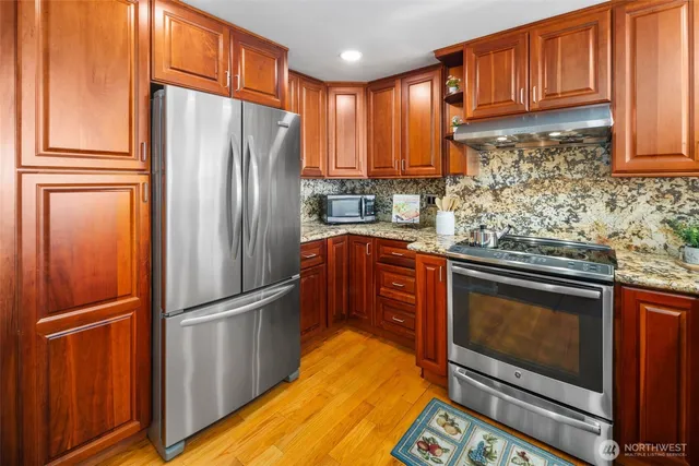 a kitchen with stainless steel appliances granite countertop a refrigerator stove and cabinets